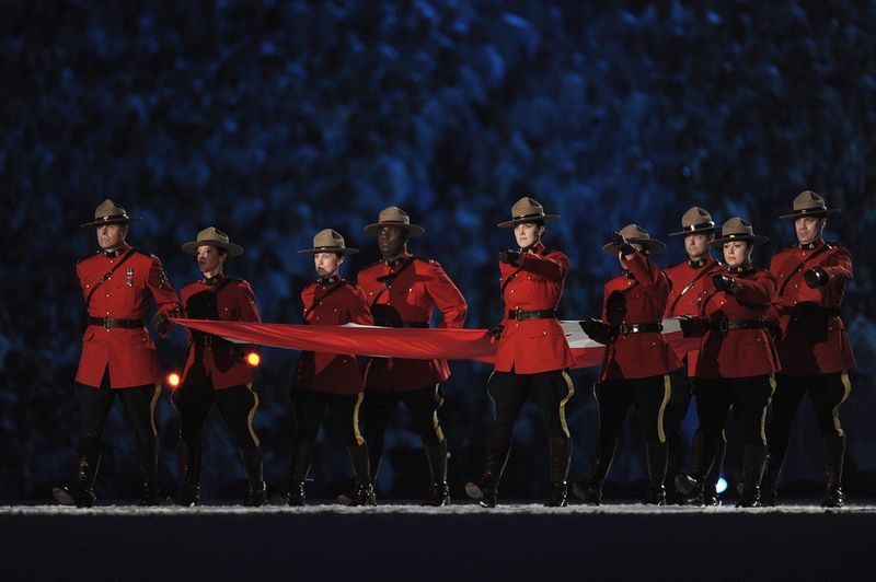 Члены Королевской канадской конной полиции несут канадский флаг на стадионе во время церемонии открытия игр.