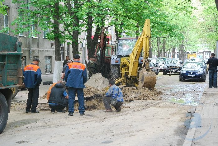 Здесь работники КП «Вода» Киевского района прокладывают новую трубу. Они обещают, что к вечеру дорога будет ровной, но пока не заасфальтированной. Через несколько дней земля осядет, тогда и уложат асфальт.