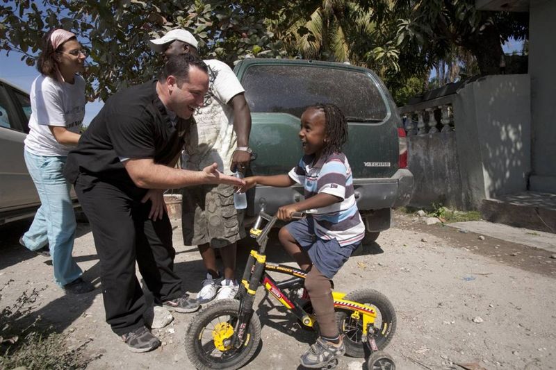 Джей Тью приветствует Шнэйли в Леогане у дома его родителей. Тью разработал протез для мальчика, который стал одним из 700 протезов, созданных и розданных в феврале в клинике для протезов в больнице Альберта Швайцера. Тью вернулся на Гаити на этой неделе, в годовщину прошлогоднего землетрясения, чтобы проверить своих пациентов. «Это все равно что вернуться домой», - сказал он. (Nadav Neuhaus for msnbc.com)