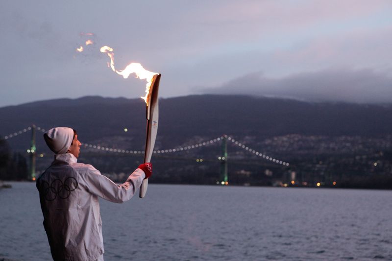 Факелоносец Тернер Сьюард несет огонь в парке Стэнли на фоне моста «Лайонс Гейт» 12 февраля.