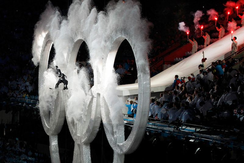 Сноубордист прыгает через кольца на церемонии открытия игр. 