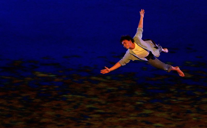 Акробат летит над сценой на церемонии открытия.