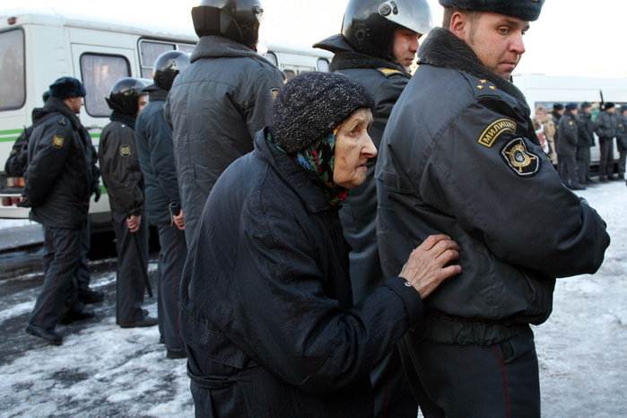 Пожилая женщина за оцеплением во время уличных беспорядков.