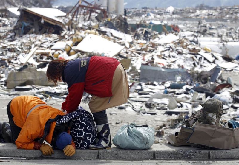 8. Люди плачут, собирая уцелевшие вещи на развалинах своего дома в деревне Оцути, пострадавшей от землетрясения и цунами.