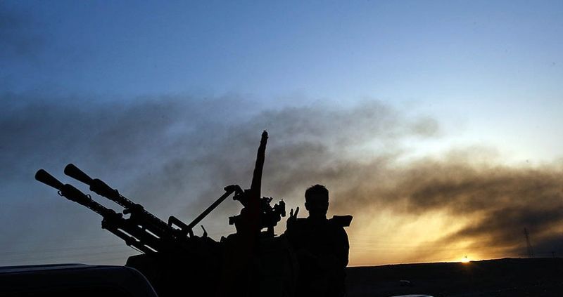 Грузовик повстанцев с пулеметом возвращается из Бен-Джаввада на фоне дымящегося заката.