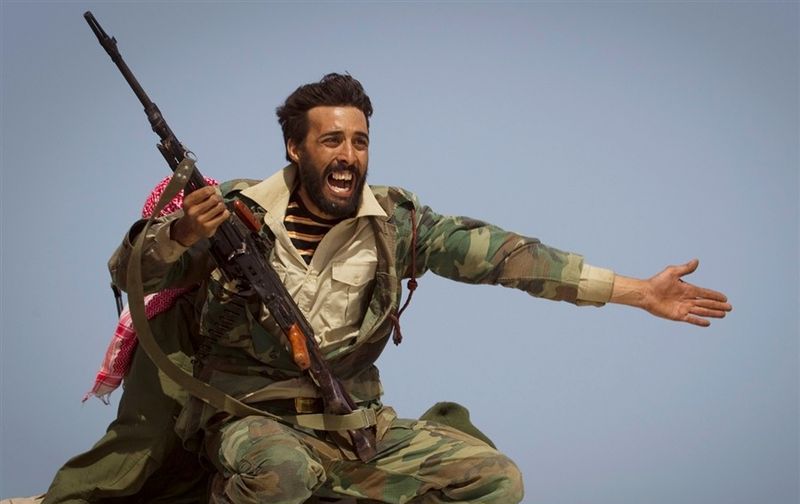 Ливийский повстанец упрашивает людей уйти из-за артиллерийского обстрела фойсками Каддафи на линии фронта у Бен-Джаввадв в 150 км к востоку от Сирте (Sirte), центральная Ливия, 29 марта 2011 года.