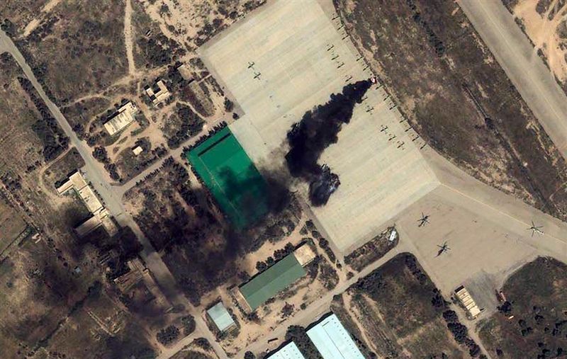 На снимке, выполненном со спутника GeoEye IKONOS, пылающий самолет на летном поле в Мисрате (Misrata), Ливия. Снимок сделан 23 марта 2011 года.