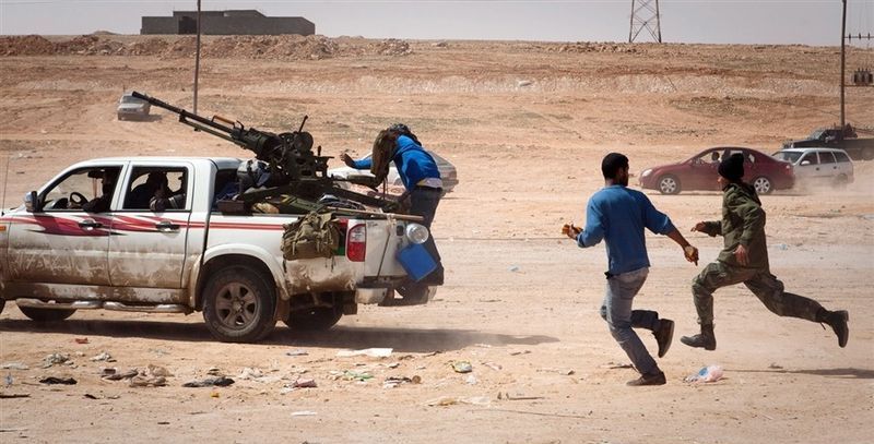 Ливийские повстанцы спасаются бегством от артиллерийского обстрела войсками Каддафи на линии фронта у Бен-Джаввада 29 марта.