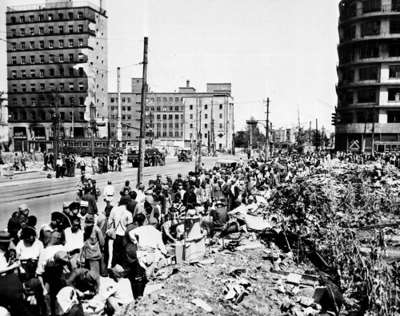  В районе Гинза города Нагасаки, который являлся аналогом нью-йоркской Пятой авеню, владельцы магазинов, разрушенных в результате взрыва ядерной бомбы, продают свой товар на тротуарах, 30 сентября 1945 года.