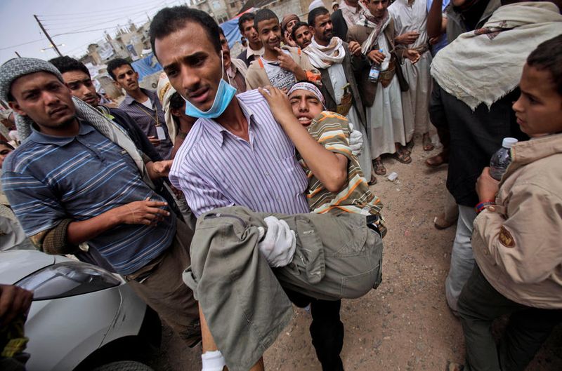Антиправительственный демонстрант помогает раненому товарищу в Сане. (AP Photo/Muhammed Muheisen)