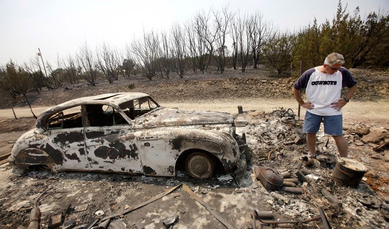 . Кент Хайден осматривает обгоревшие останки гарада своих родителей и то, что осталось от недавно восстановленного старинного «Jaguar», после того как лесной пожар прошелся по Поссум Кингдом 16 апреля. (AP Photo/LM Otero)