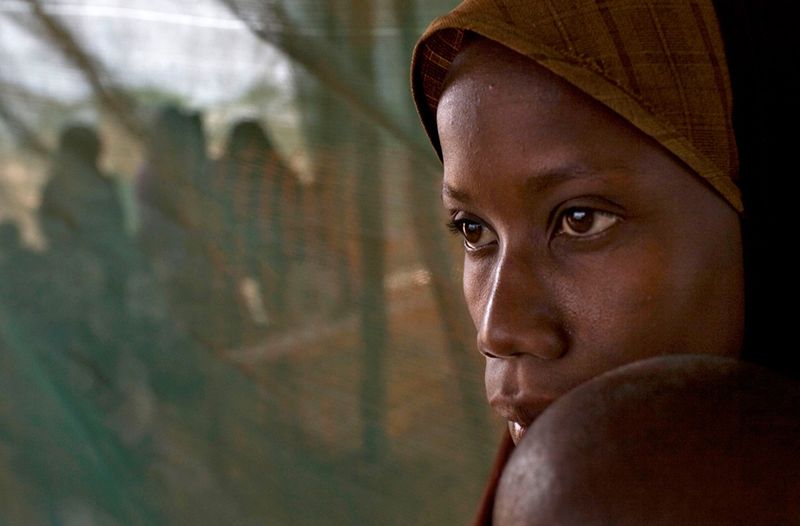 12. Сомалийская беженка держит на руках ребенка, ожидая распределения продуктов питания в клинике медицинской благотворительной организации «Врачи без границ» в лагере Дагахали в Дадаабе на северо-востоке Кении, 7 июня 2009 года. (Reuters/Finbarr O'Reilly)
