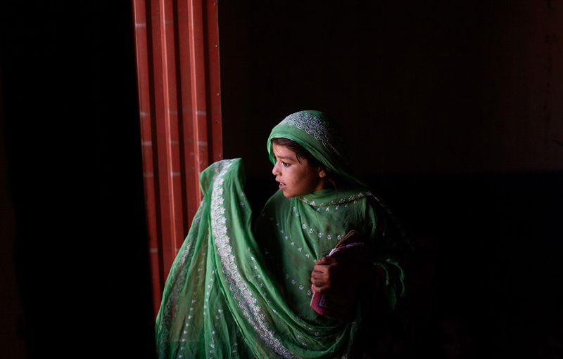 Пакистанская девочка у окна мечети на ежедневном религиозном уроке в трущобах на окраине Исламабада. (AP Photo/Muhammed Muheisen)