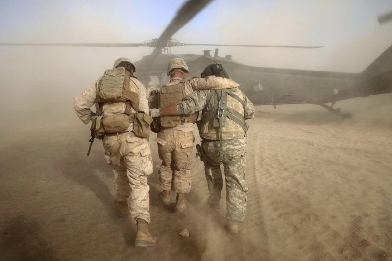  Медик армии США Хайме Адаме, справа, и неизвестный солдат морской пехоты США помогают солдату морской пехоты Крису Пропсту из Южной Каролины, в центре, который был ранен во время повстанческих атак, перейти в санитарный вертолет к северу от Сангин, в провинции Гильменд на юге Афганистана, воскресенье, 15 Мая 2011 года.