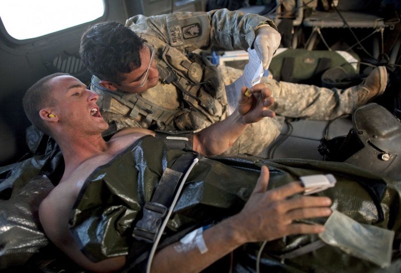 Медик армии США Хайме Адаме, справа, слушает, как солдат морской пехоты США Крис Пропст из Южной Каролины, который был ранен во время повстанческих атак, рассказывает о своих ранах на борту санитарного вертолета к северу от Сангин, в провинции Гильменд на юге Афганистана, воскресенье, 15 Мая 2011 года.