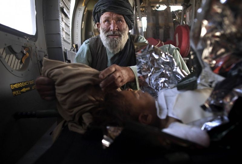  Родственник рядом с раненным афганским мальчиком, который получил ожоги, в санитарном вертолете Целевой группы армии США “Dust Off,” 1-214 авиационного полка из Мусса Кала в зоне конфликта к северу от Сангин, в провинции Гильменд на юге Афганистана, воскресенье, 11 мая 2011 года.
