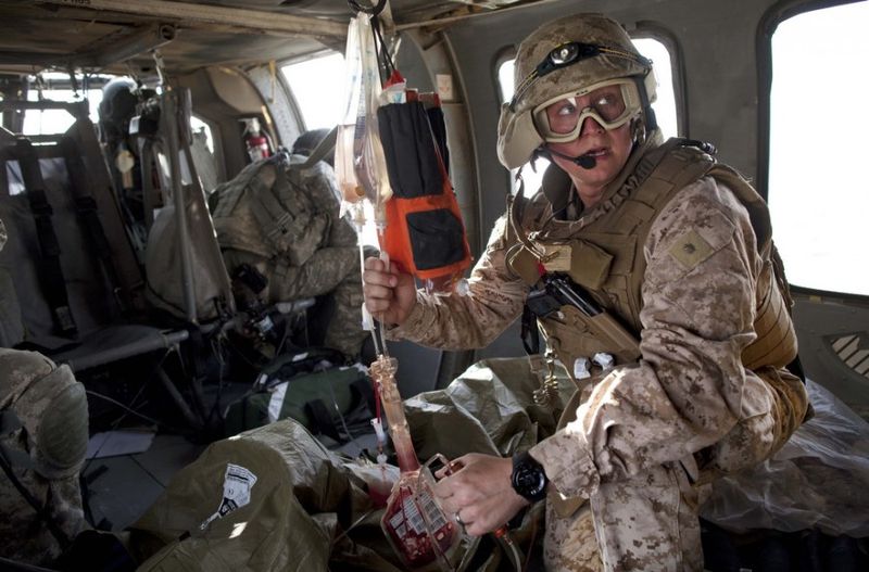 Эрик Грин из Мичигана оказывает помощь раненному афганцу по пути в госпиталь на борту санитарного вертолета Целевой группы армии США “Dust Off,” 1-214 авиационного полка в районе Сангин в провинции Гильменд на юге Афганистана, воскресенье, 8 мая 2011 года.