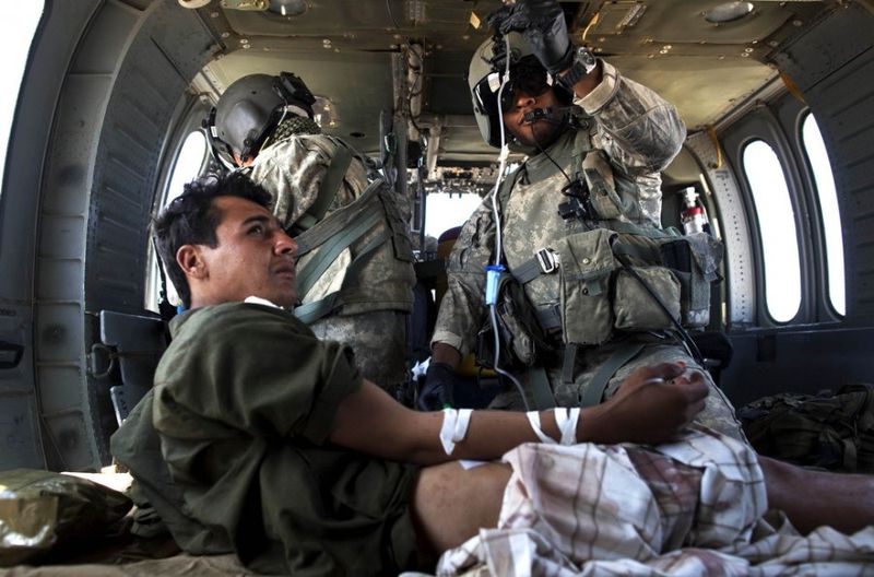 Медик Торрел Брайан держит капельницу раненному афганцу на борту санитарного вертолета Целевой группы армии США “Dust Off,” 1-214 авиационного полка в районе Сангин в провинции Гильменд на юге Афганистана, пятница, 6 мая 2011 года.