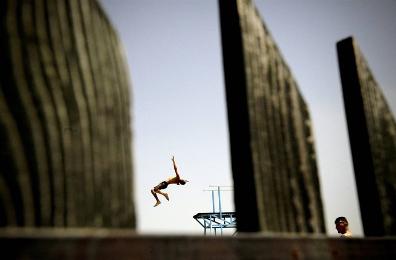 Мальчик из Косово прыгает в воду в бассейне рядом с деревней Милосево 25 июля, спасаясь от жары в 40 градусов по Цельсию.