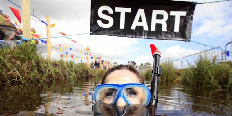 Участница чемпионата по плаванию в болоте в Северной Ирландии пересекает линию старта/финиша, парк Питлэндс, Ирландия, 26 июля.