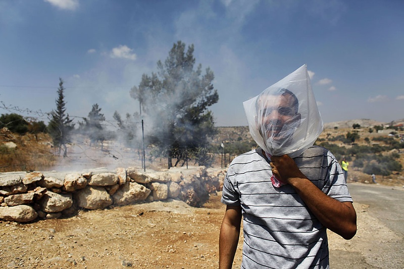 Палестинский демонстрант надел на голову целлофановый пакет, так как израильские солдаты выпустили слезоточивый газ во время акции протеста в пятницу в Билине, Западный берег реки Иордан. (Uriel Sinai/Getty Images)