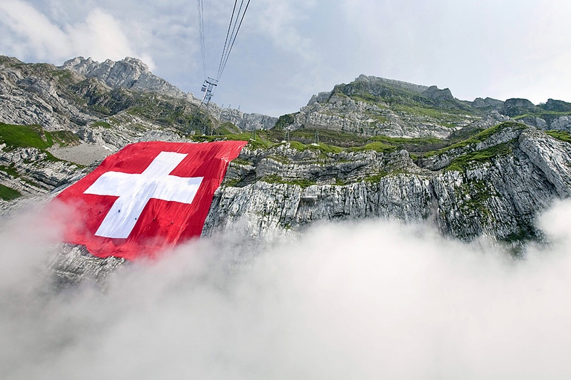 Самый большой в мире швейцарский флаг и второй по величине флаг в мире свисает с гор Сантис в Швагальпах, Швейцария, пятница. В субботу в Швейцарии прошел общегосударственный праздник. (Ennio Leanza/Keystone via Associated Press)