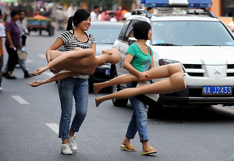 Девушки несут манекен, направляясь к своему магазину на одной из улиц в Хэфэй, китайская провинция Аньхой, пятница. (Agence France-Presse/Getty Images)