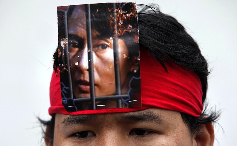 Жители Мьянмы в Тайланде съехались на митинг перед посольством Мьянмы в Бангкоке в пятницу. Протестанты взывали отпустить продемократического лидера Аун Сан Су Чжи, чью фотографию можно видеть на повязке на этом снимке. Суд Мьянмы отложил вердикт по делу мисс Аун до 11 августа. (Chaiwat Subprasom/Reuters)