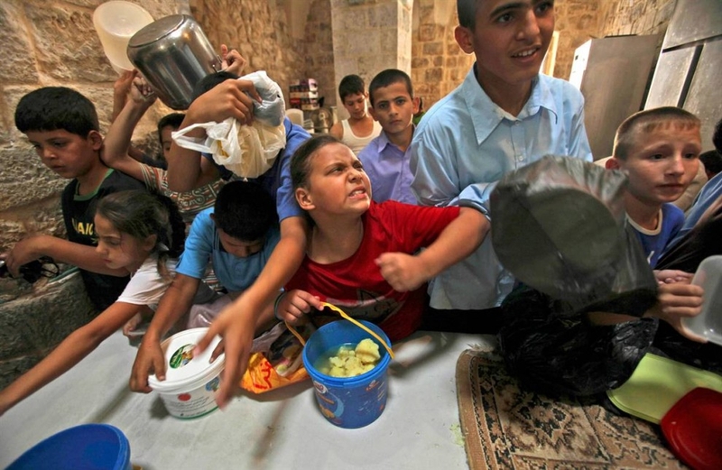 Палестинская девочка бьет локтем в бок мальчика во время раздачи продовольственных пайков в Старом городе Иерусалима 8 сентября.