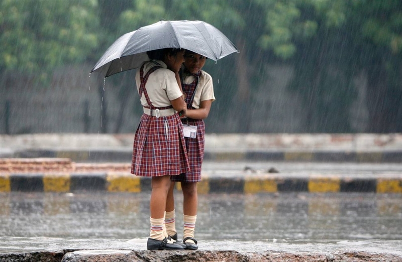 Индийские школьницы стоят на разделительной полосе во время муссонного дождя в Нью-Дели, 10 сентября.