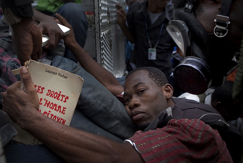 Штурмовая полиция задержала студента с книгой, на которой написано по-французски «Права человека и гражданина», в Порт-о-Пренс, Гаити, в среду. Участники акции протеста выступали с требованиями о повышении зарплаты, модификации в учебном плане и другие изменения.