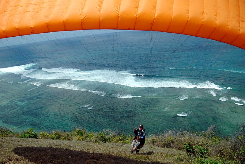 Мужчина прыгает с парапланом со склона в Timbis, Jimbaran, на индонезийском острове Бали. Парапланёры используют для подъема вверх воздушные потоки.