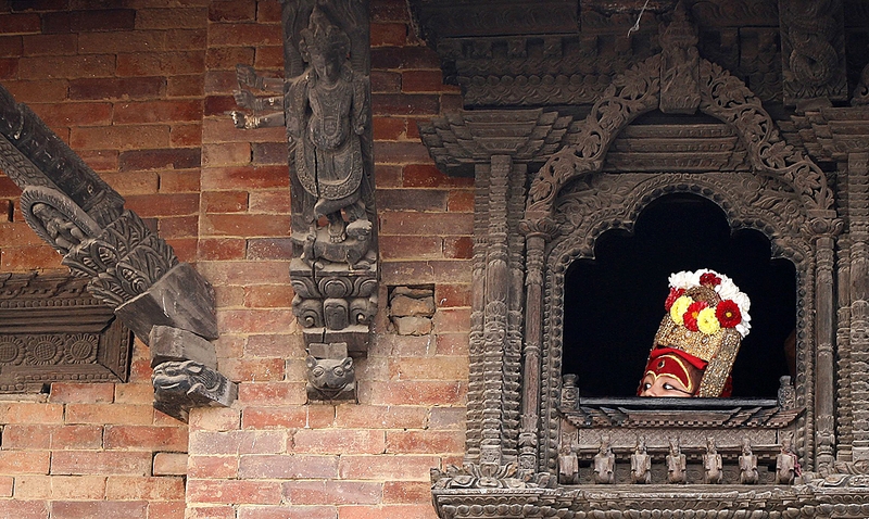 Мальчик, одетый как бог Ганеша, выглядывает из окна, прежде чем предстать с публикой во время фестиваля Индра Джатра в Катманду, Непал. 