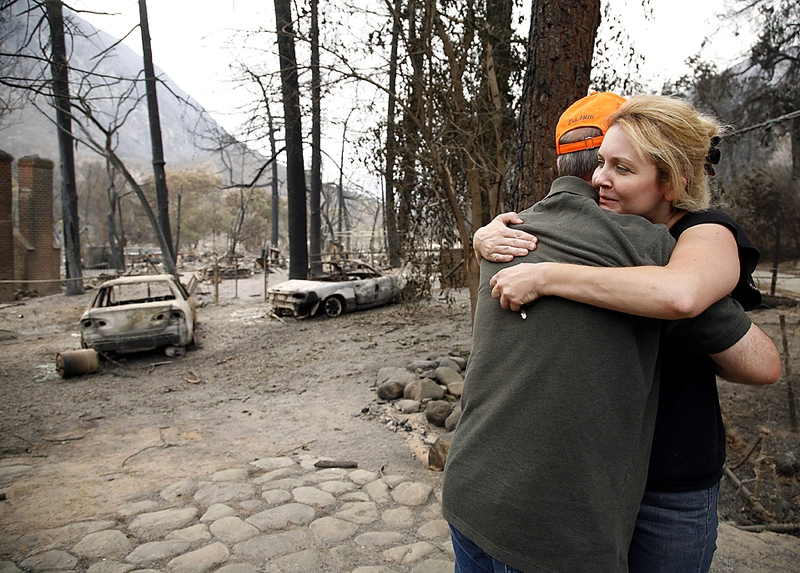 Синди Пейн сдерживает слезы, обнимая своего соседа, Дэйва Джонсона, недалеко от Лос-Анджелеса в прошлый четверг. Оба они лишились своих домов 30 августа во время массовых пожаров, которые, как считают власти, были вызваны поджогом