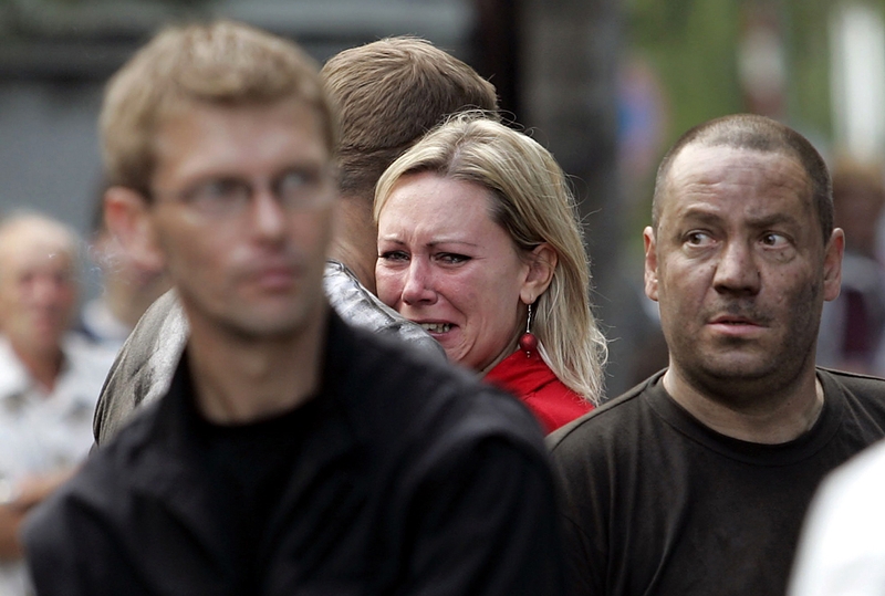 Люди стоят у шахты в польском городе Руда Сленска, где погибли 12 и были тяжело ранены 15 шахтеров после взрыва метана в пятницу.