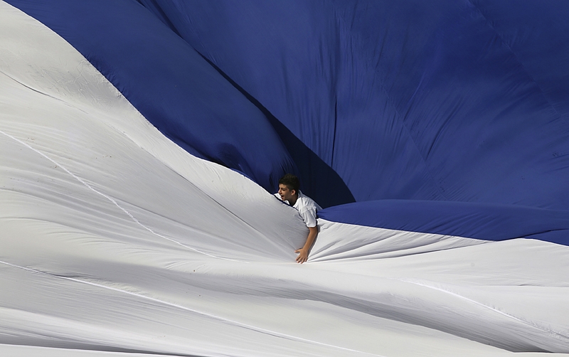 Израильский школьник играет в большом флаге в Иерусалиме. Флаг, занесенный в книгу рекордов Гиннесса как самый большой в мире, был развернут на стадионе Тедди в Иерусалиме в четверг.
