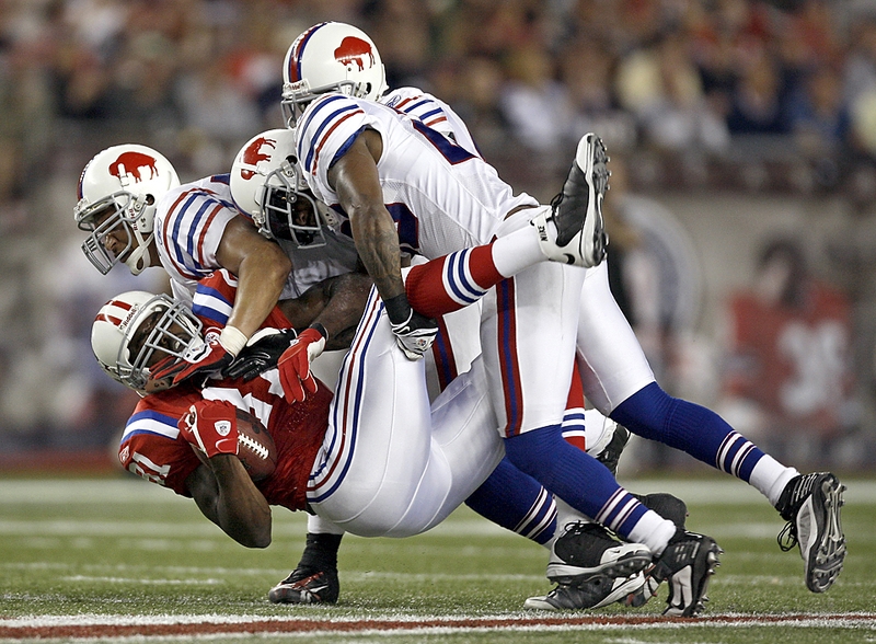 Игроки команды «Buffalo Bills» Кейт Эллисон, Донте Витнер и Брайан Скотт роняют на землю игрока из команды «New England Patriots» Ренди Мосса во время футбольного матча в Foxborough, штат Массачусетс.