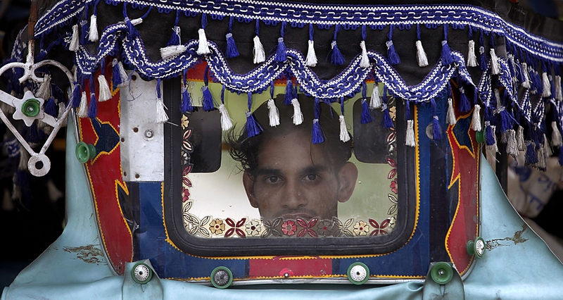 Человек смотрит сквозь лобовое стекло повозки рикши в пакистанском районе Бунер