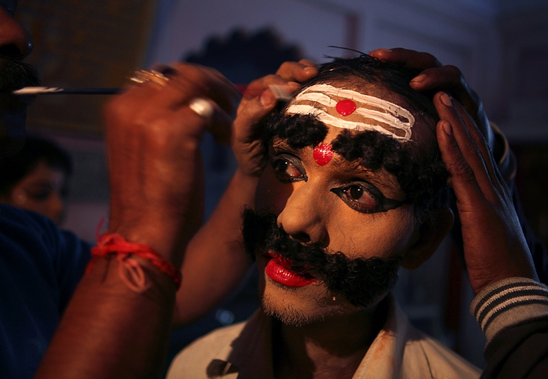 Мальчику, одетому как Равана, король демонов в индуистской мифологии, раскрашивают лицо перед началом шествия в Аллахабаде, Индия.
