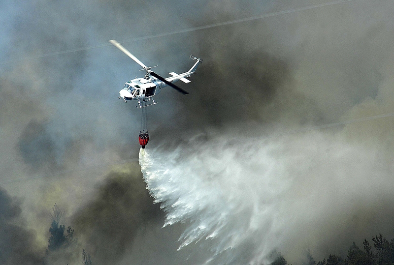 Вертолет сбрасывает воду на пожар, бушующий к северу от Елены, штат Монтана