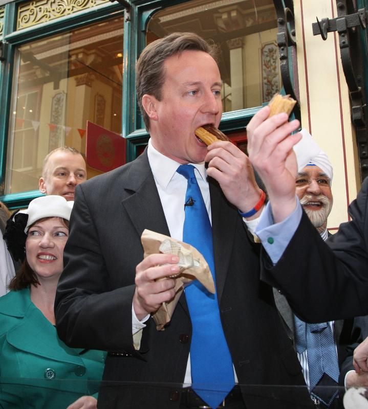 Девид Кемерон ест пирожное перед объективами камер, после своего избрания на пост премьер-министра Великобритании.
