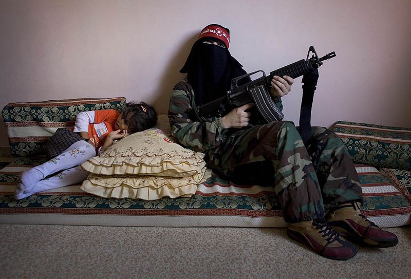 Омм Ахмед, справа, женщина-боевик из Демократического фронта по освобождению Палестины позирует фотографу в доме своего товарища по оружию в секторе Газа. Основанная в 1969 году, ДФОП насчитывает около 40 женщин, проходящих специальную подготовку, которая началась шесть месяцев назад в качестве ответа на январское наступление Израиля.